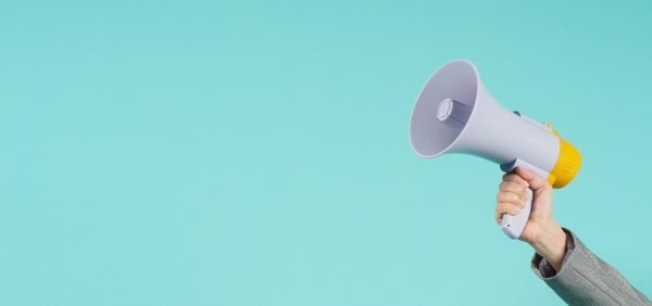 Hand is hold megaphone and wear grey suit on green or mint or Tiffany Blue  background.